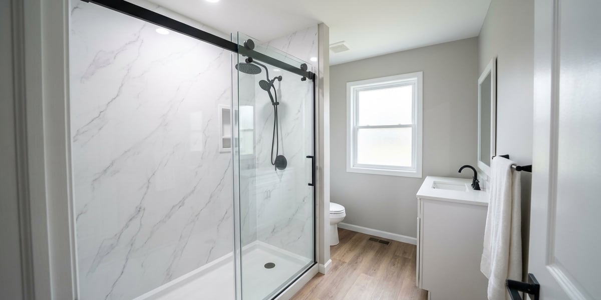 A newly finished marble-look walk-in shower with a frameless glass door